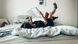 Eine junge Frau liegt entspannt im Bett und liest ein Buch in ihrem Schlafzimmer.